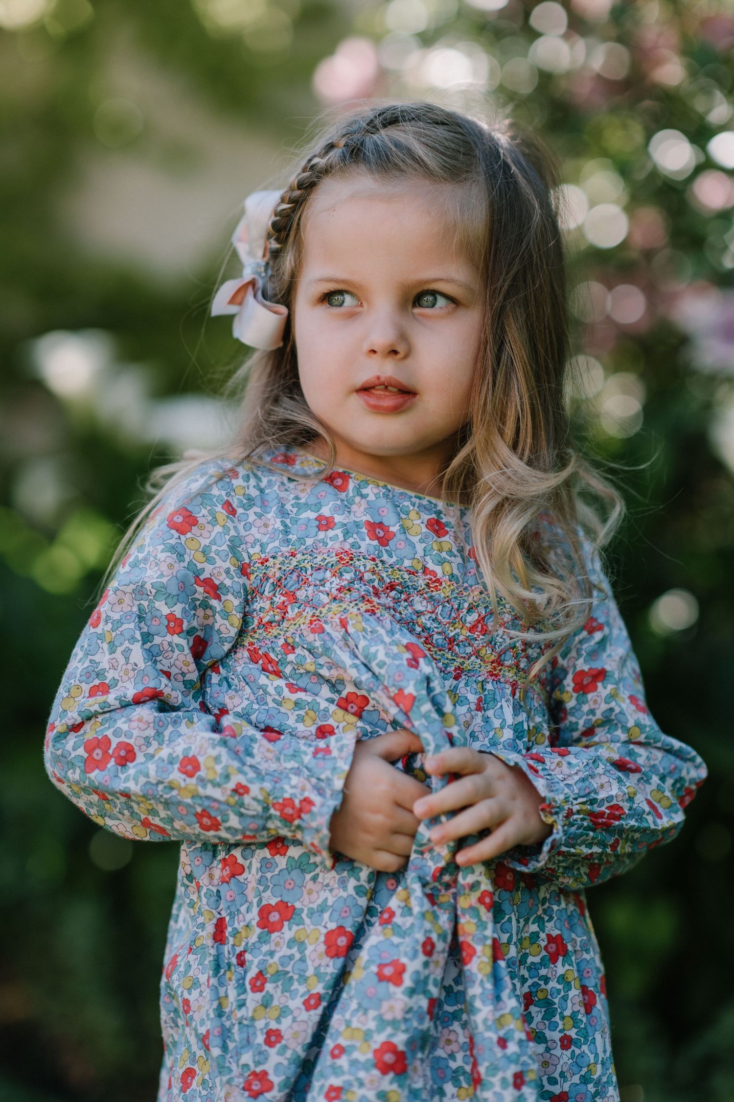 Sweet moments captured in a blue floral dress against bokeh garden lighting.