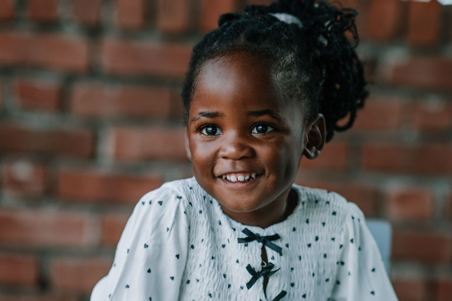 Cheerful portraits in white polka dot clothing against red brick wall.