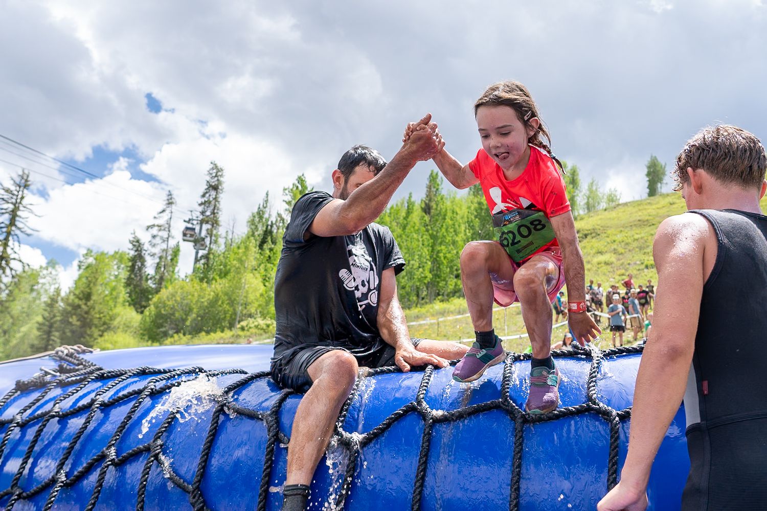 man helping kid get out of pool at go pro mountain games