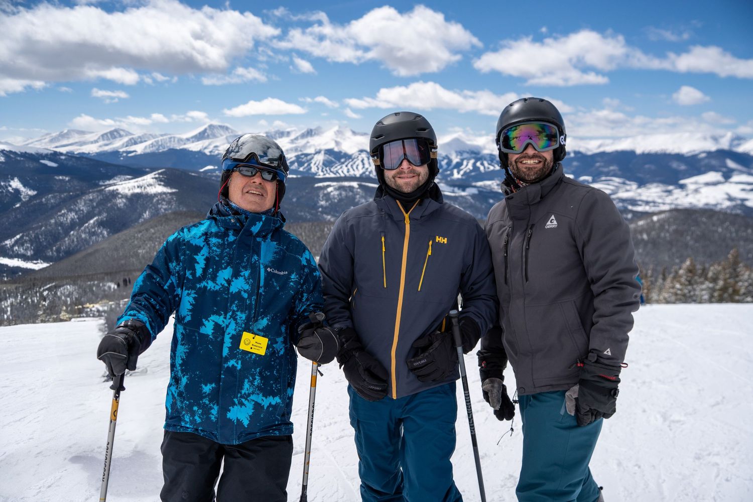 three skiers posing at the top of a mountain