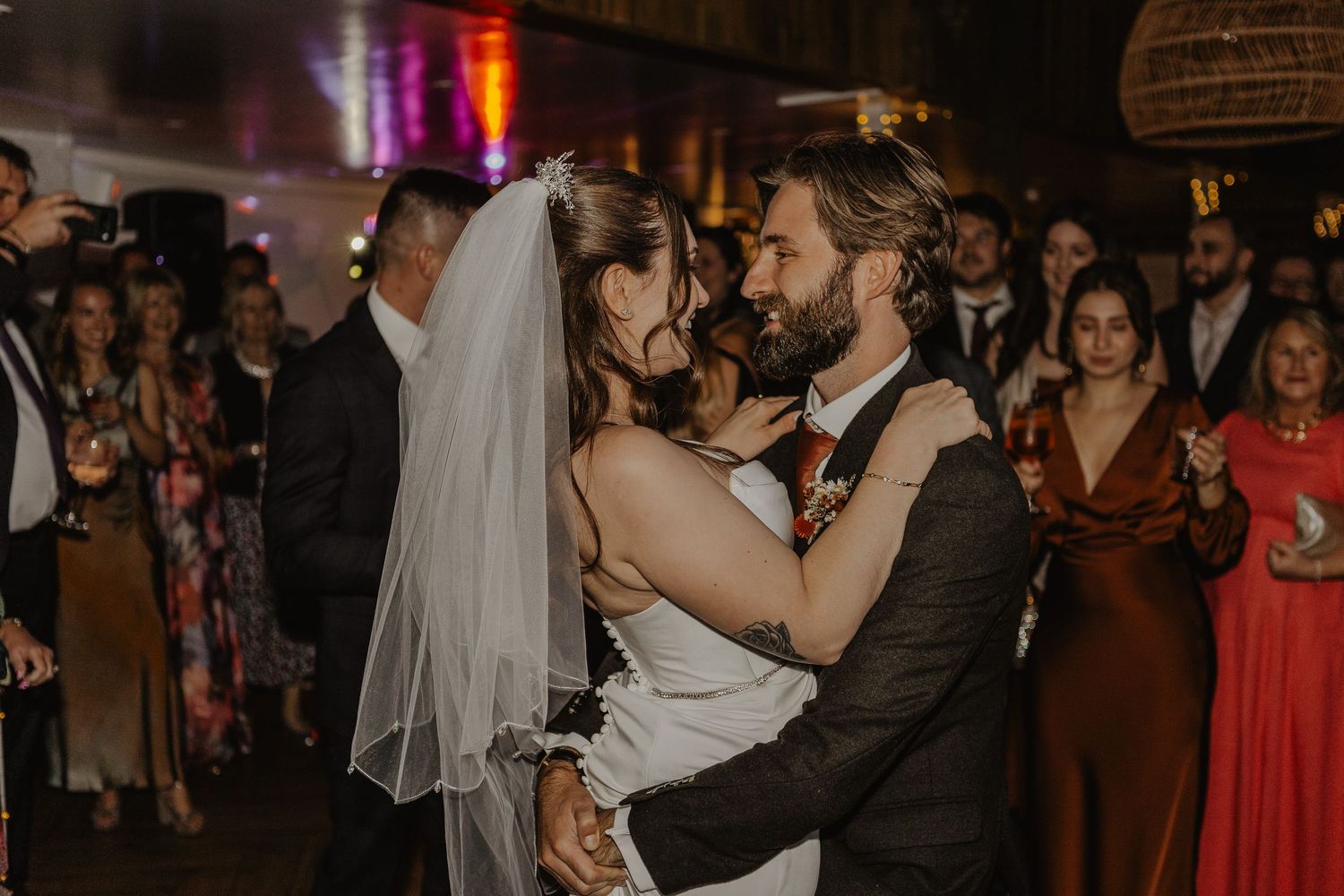 Wedding reception dance floor scene with warm lighting and guests celebrating.