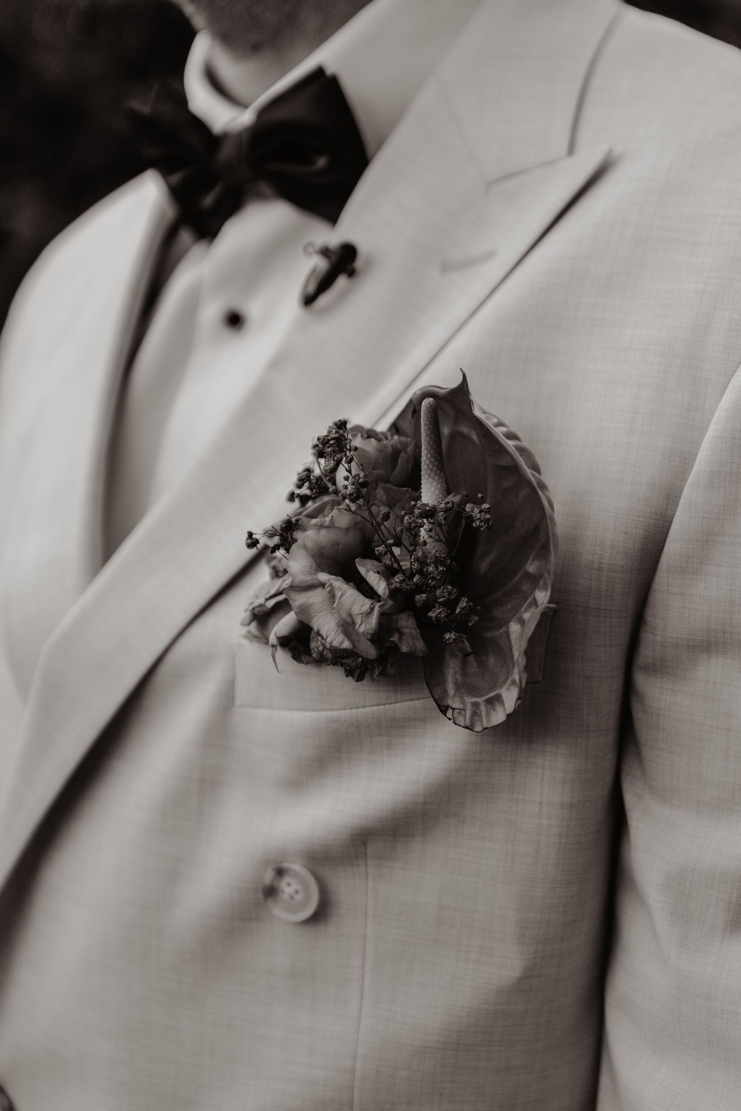 A series of black and white photographs showing a white suit jacket with a dark floral boutonniere in the lapel.