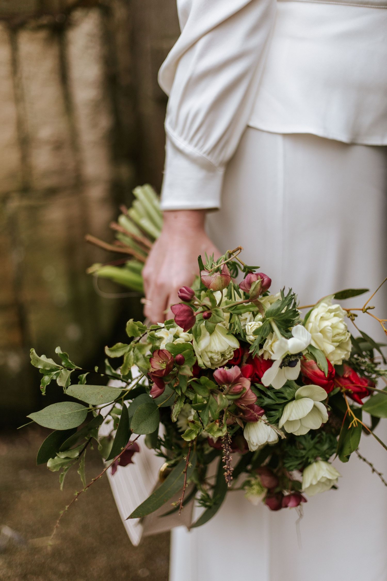 A cascading bridal bouquet with red and white flowers and greenery shown from different angles against a dark background.