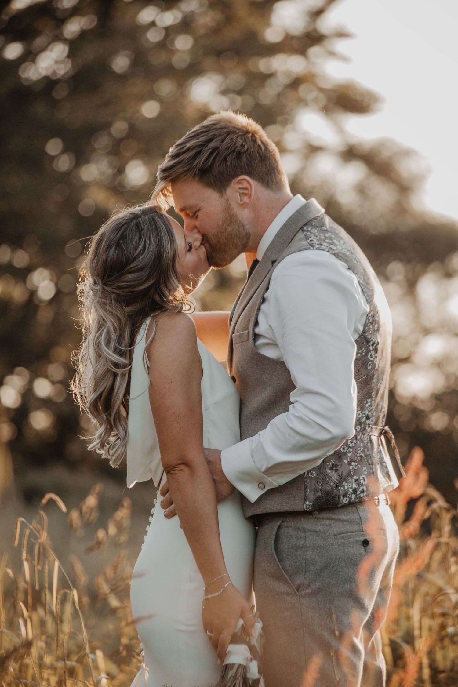 Romantic golden hour portraits of newlyweds in a sun-lit field.