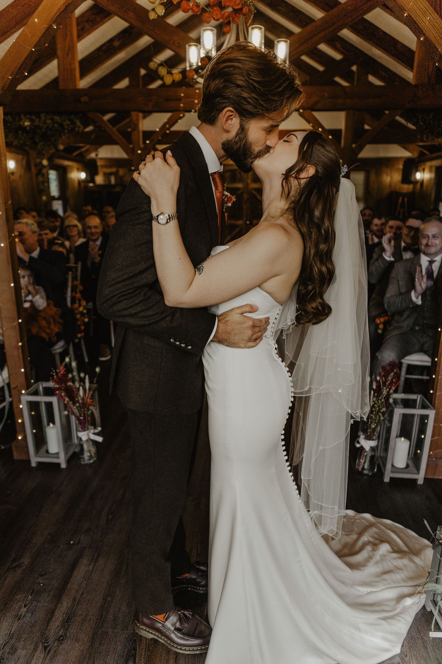 Romantic first dance moment captured in rustic wooden beam venue with warm lighting.