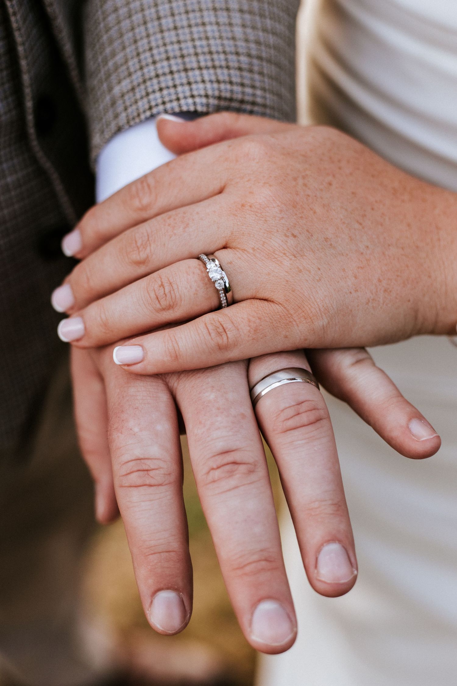 Close-up view of hands wearing wedding rings and engagement rings showing multiple angles of the jewelry.
