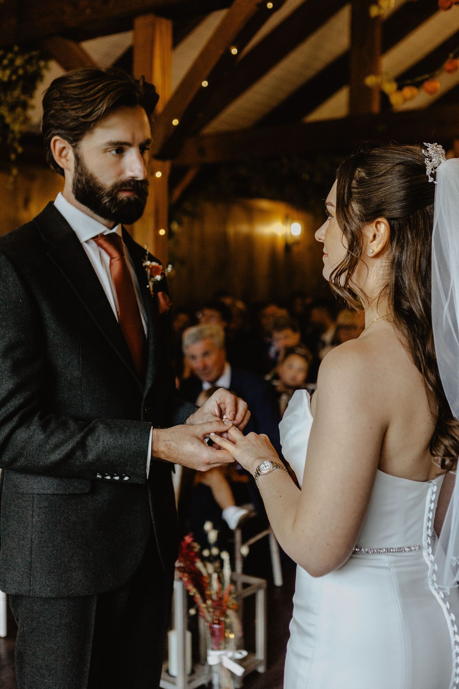 A couple shares an intimate moment during their first dance in a warmly lit rustic barn wedding venue.