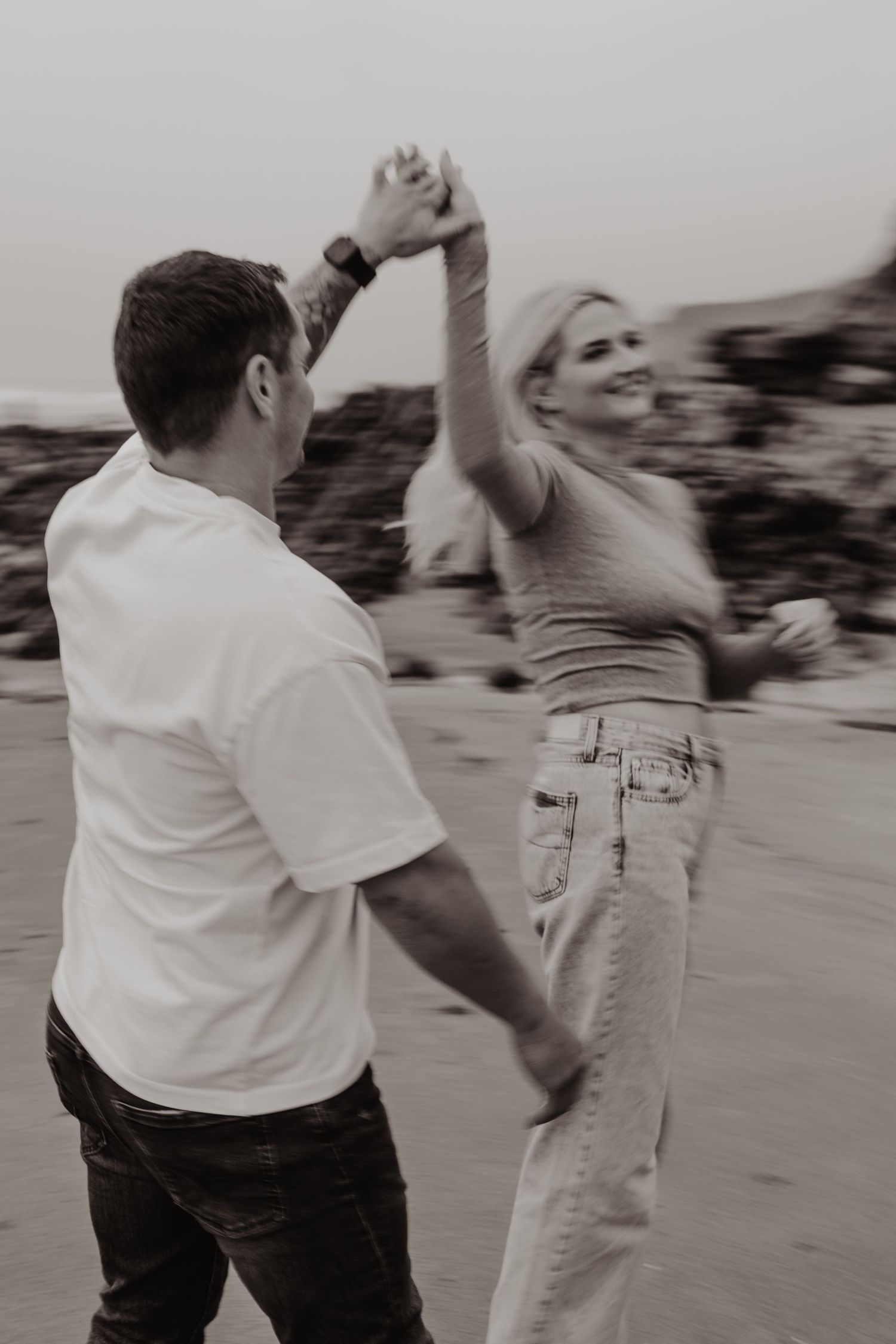 Black and white sequence of a couple dancing joyfully on the beach.