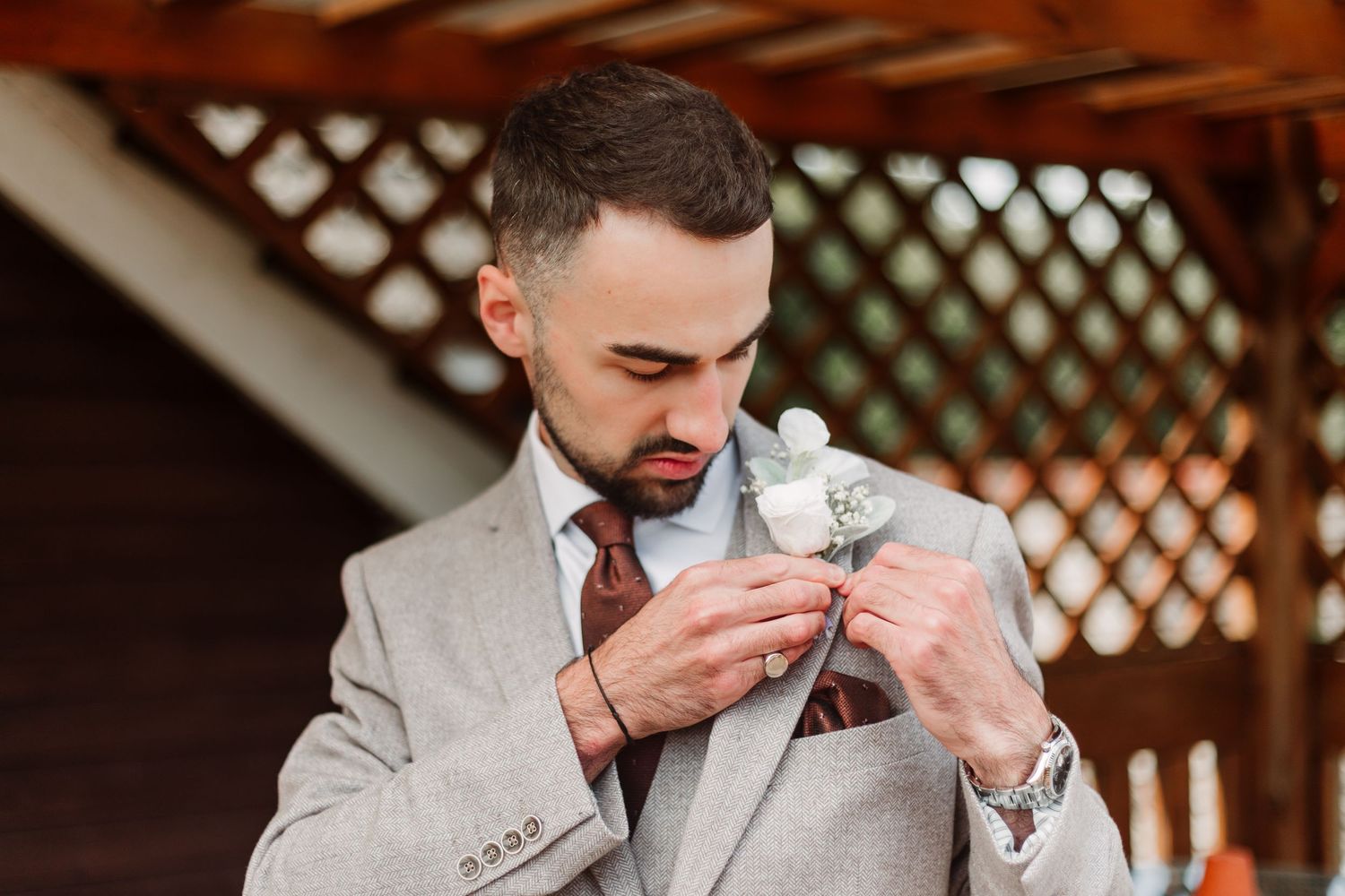 A sequence of photos showing a person in a light gray suit smelling a white boutonniere flower.