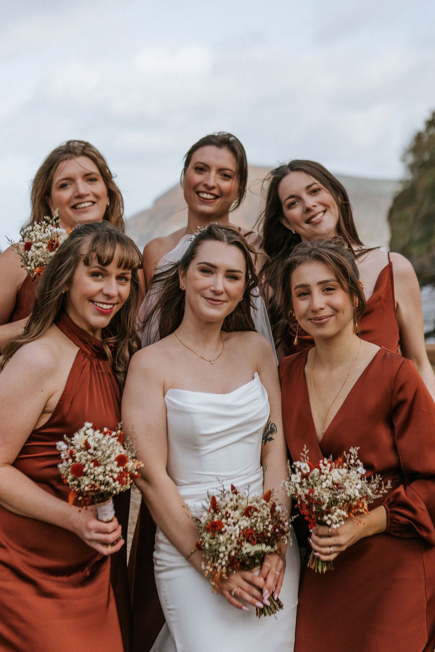 A wedding party in burgundy dresses and a white gown share joyful candid moments in a series of four photos.