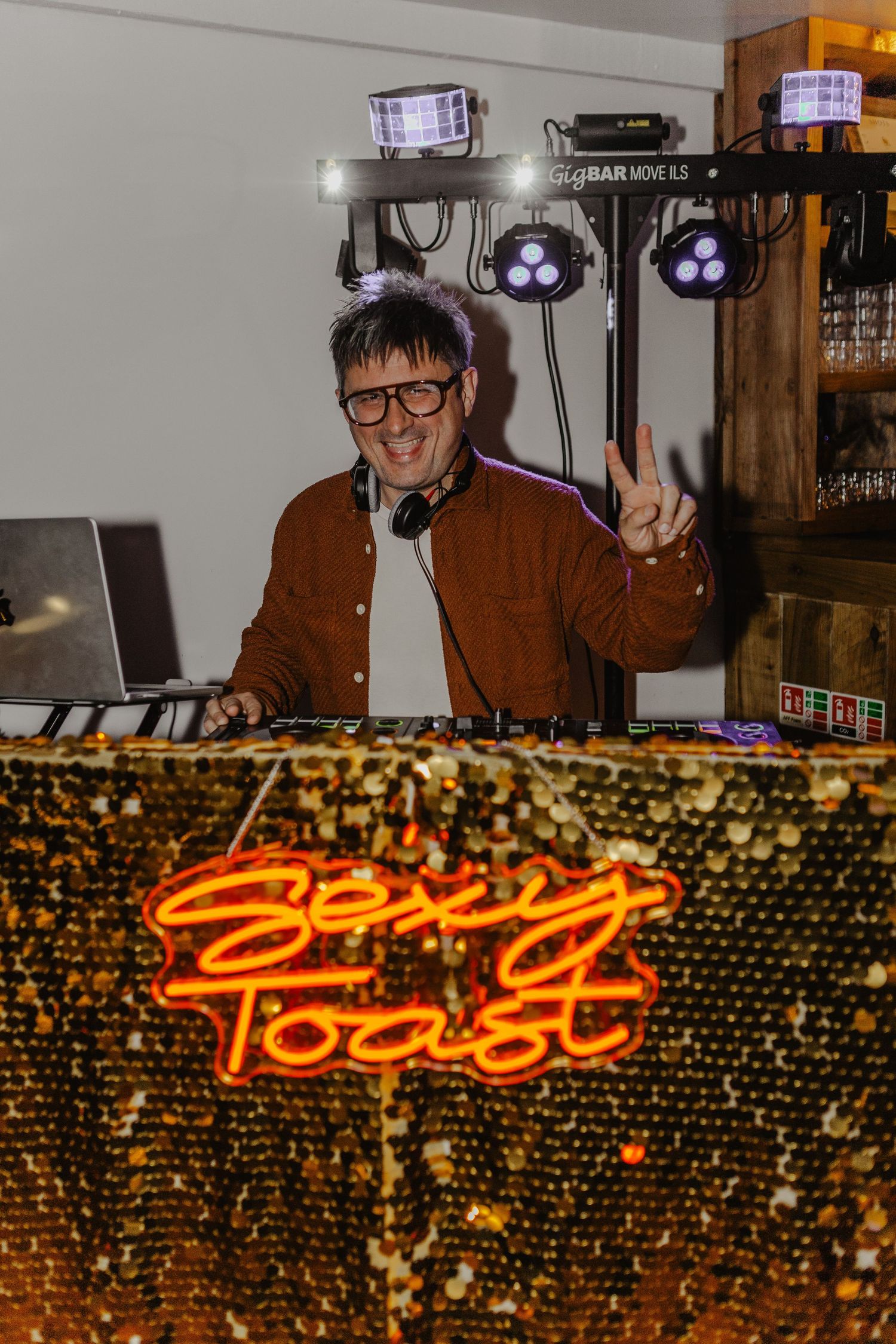 Illuminated neon sign reading 'Toast' against a glittering gold sequined backdrop.