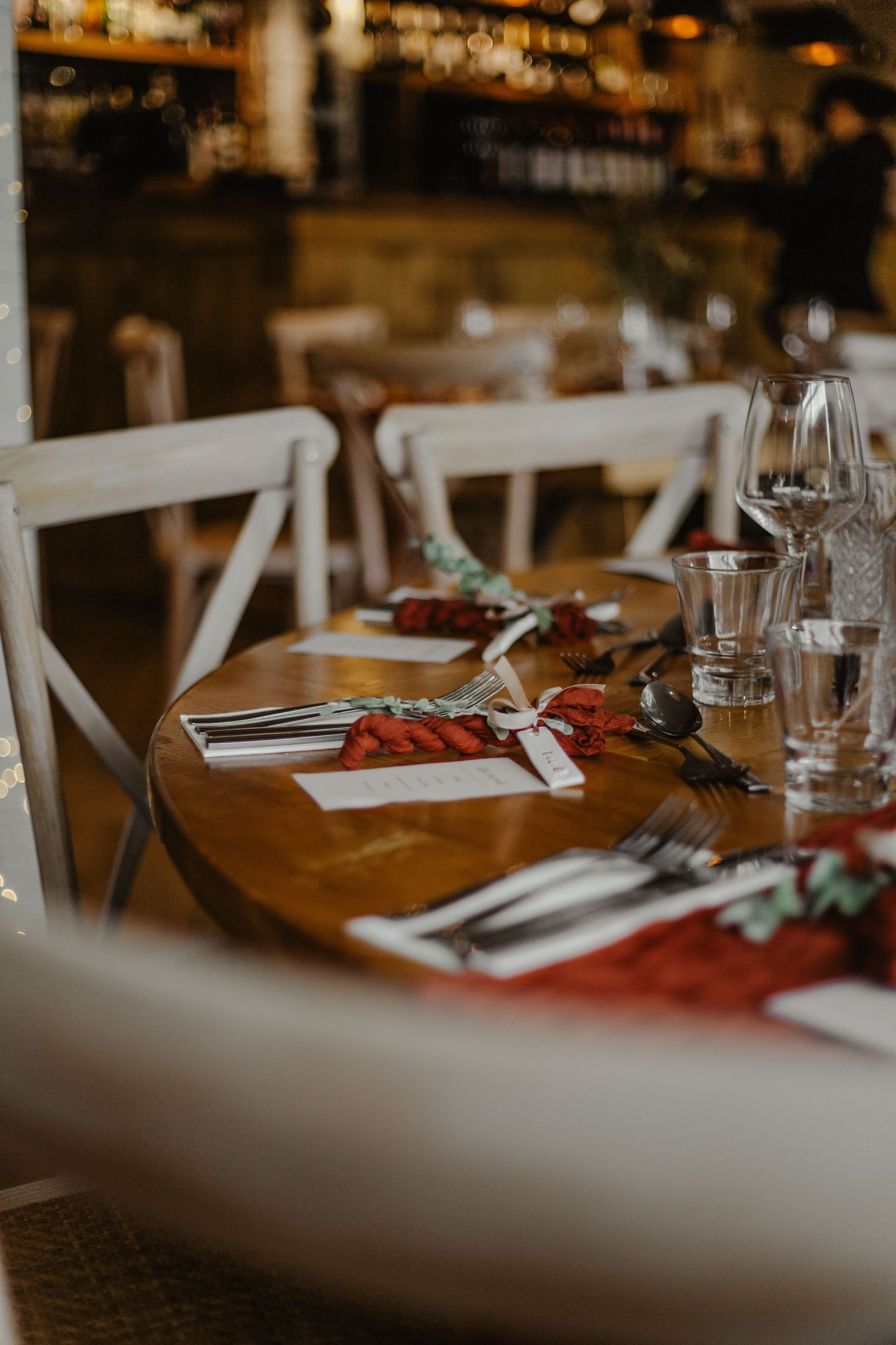 Elegant table setting with wine glasses and place settings in warm ambient lighting.