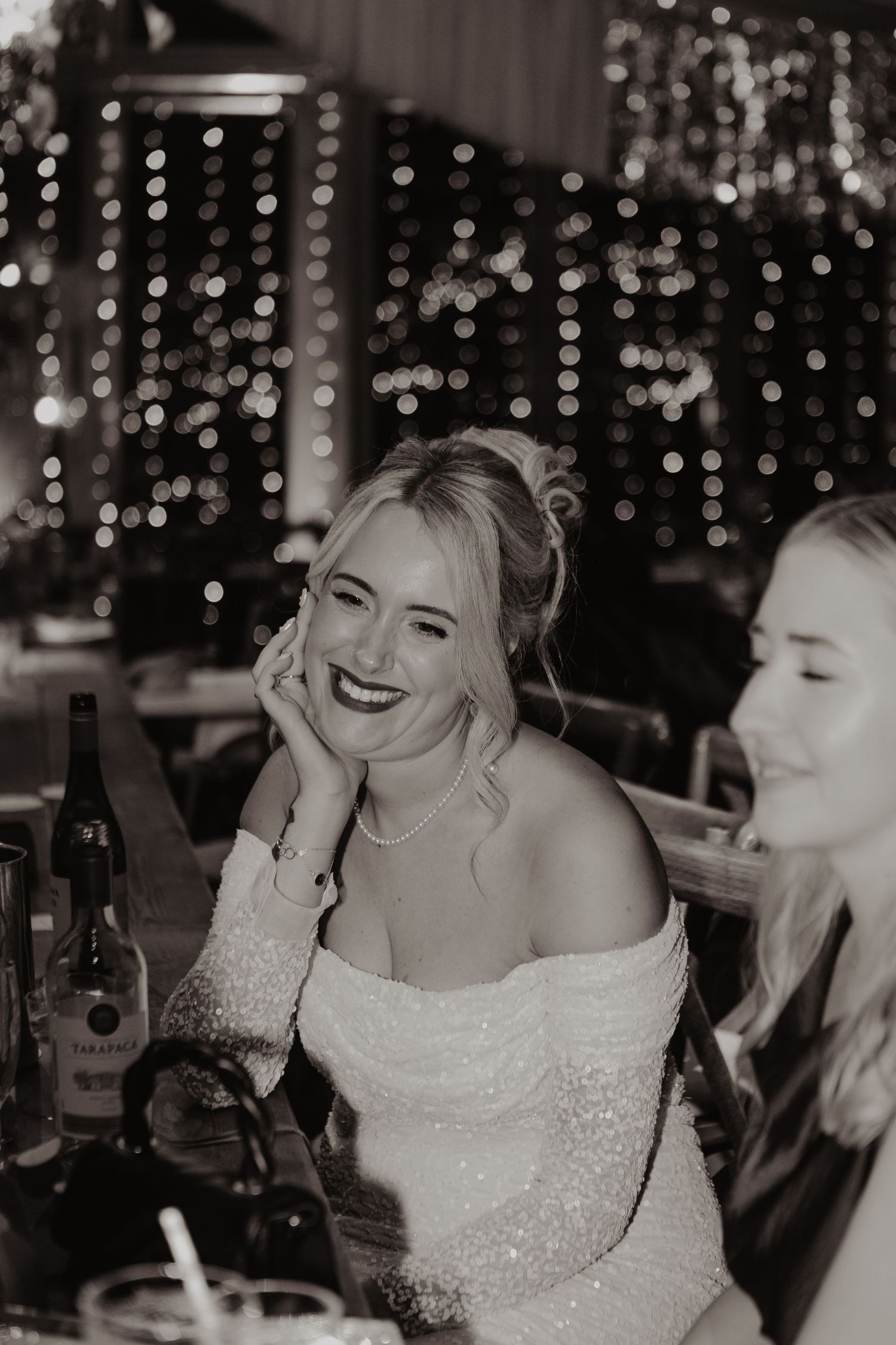 A black and white photo series showing joyful moments at a wedding celebration with twinkling lights in the background.