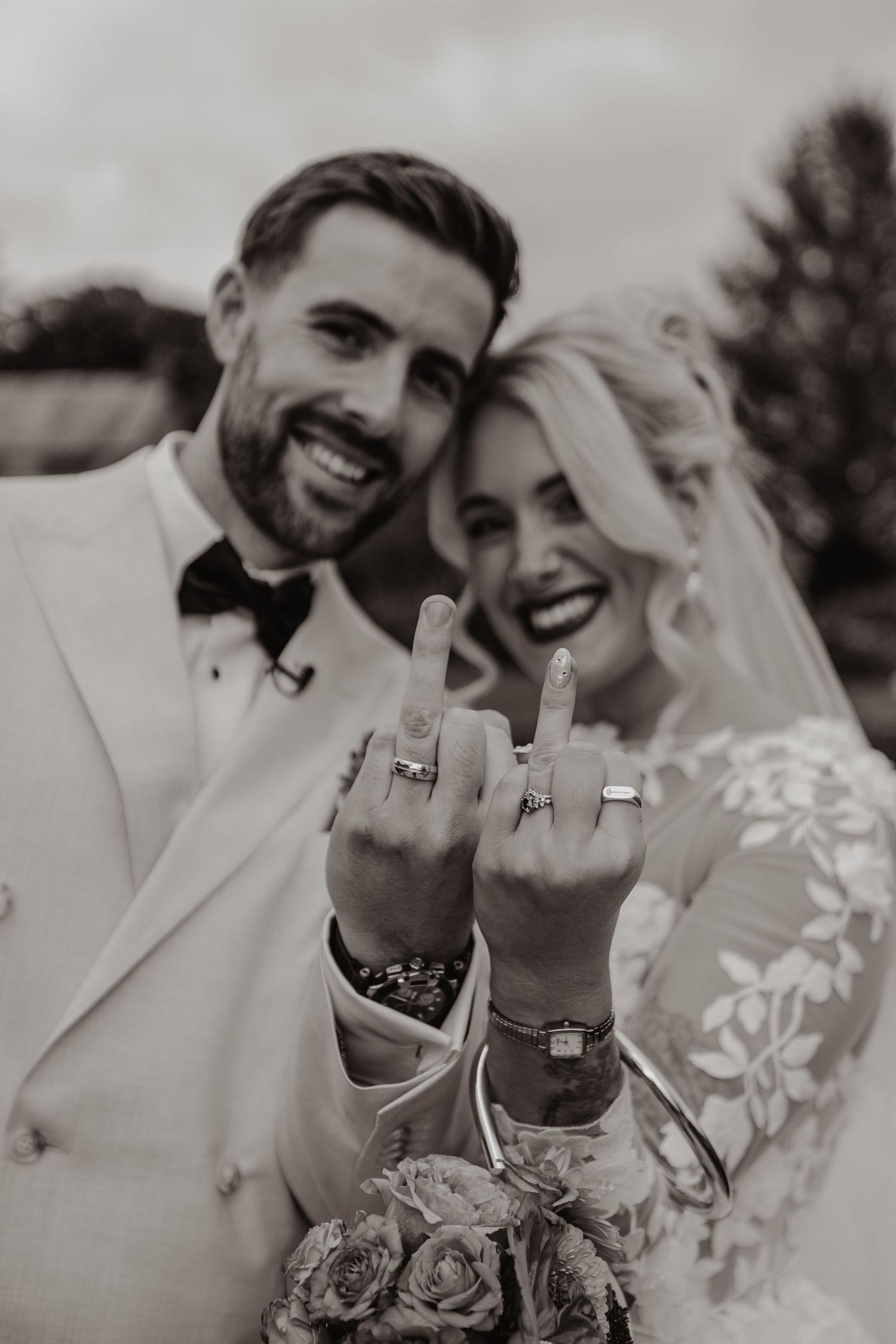 Close up of wedding rings being shown by a couple in black and white photography.