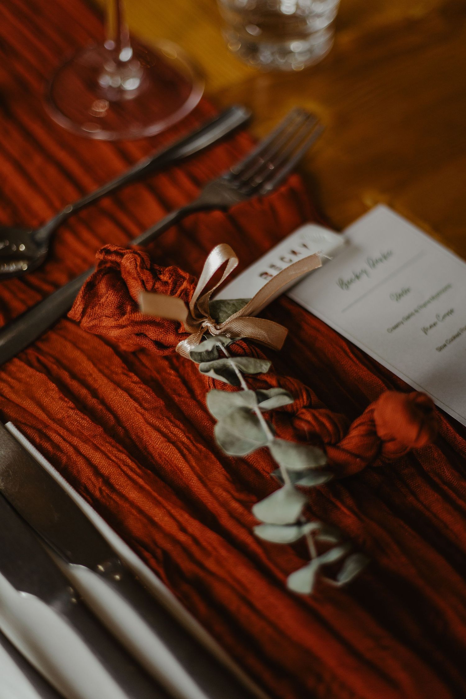 Place settings on a rustic wooden table with cutlery and name cards for an elegant dining event.