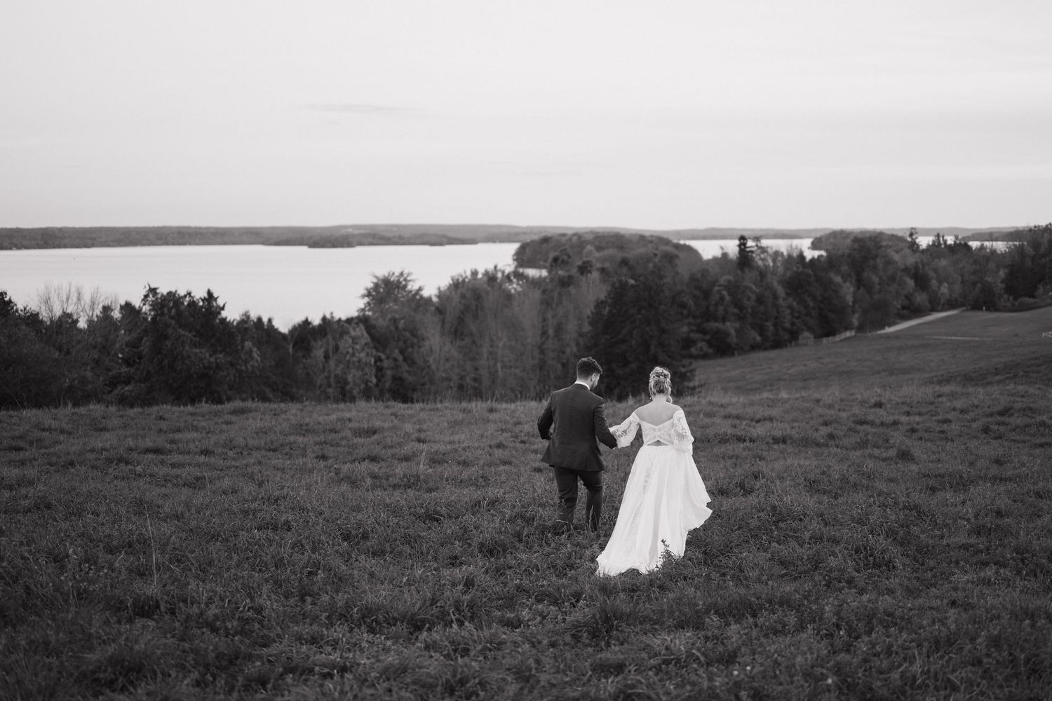 Couple running through feild at Elmhirst Resort, Keene, ON