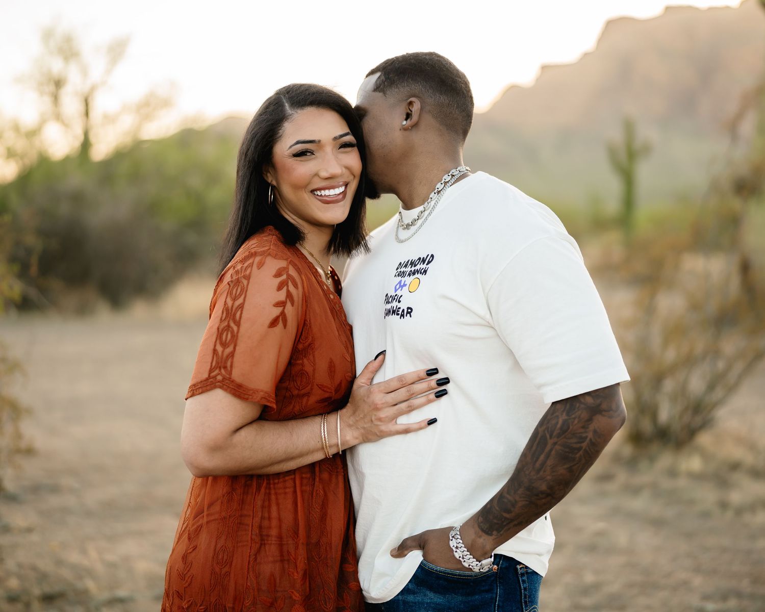 A tender moment captured in a desert landscape with saguaro cacti in the background.