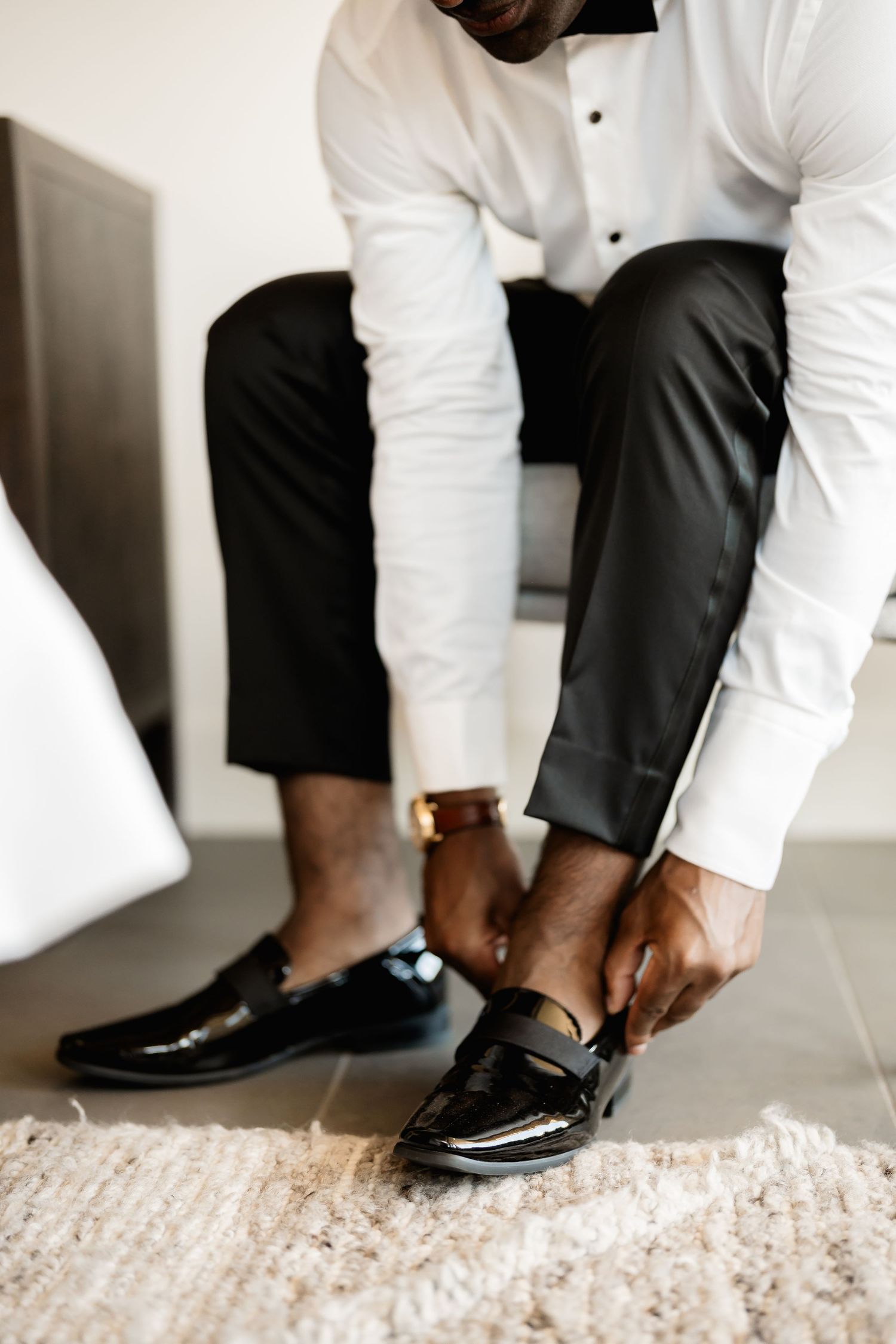 Close-up of formal black dress shoes being put on with white shirt and black pants.