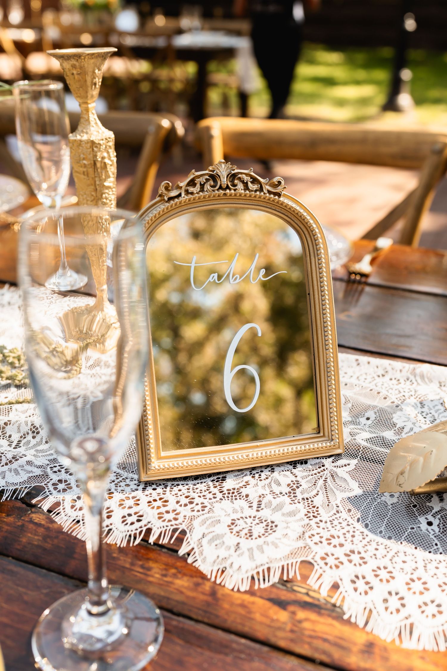 Vintage gold frames and delicate lace doilies create elegant table settings for a wedding reception.