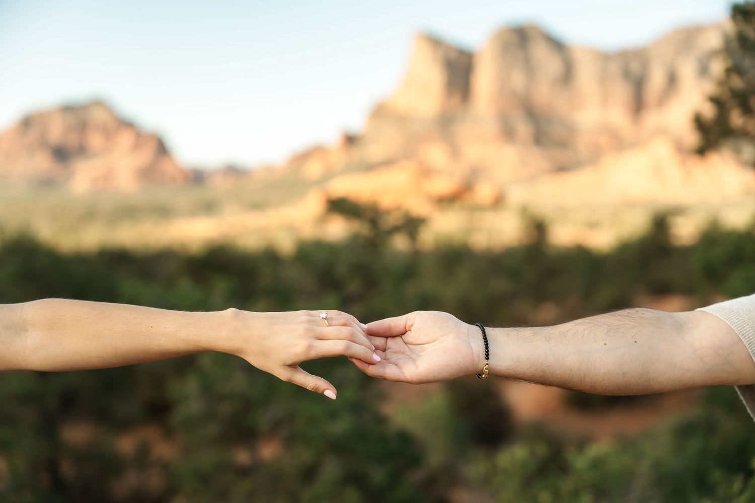 Reaching hands frame the sweeping desert vista and red rock formations.