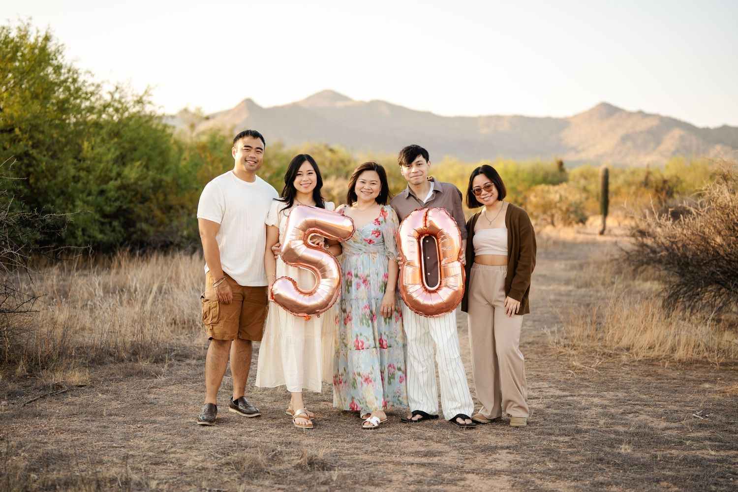 Family holding letter cutouts spelling S O N with mountains in the desert background.