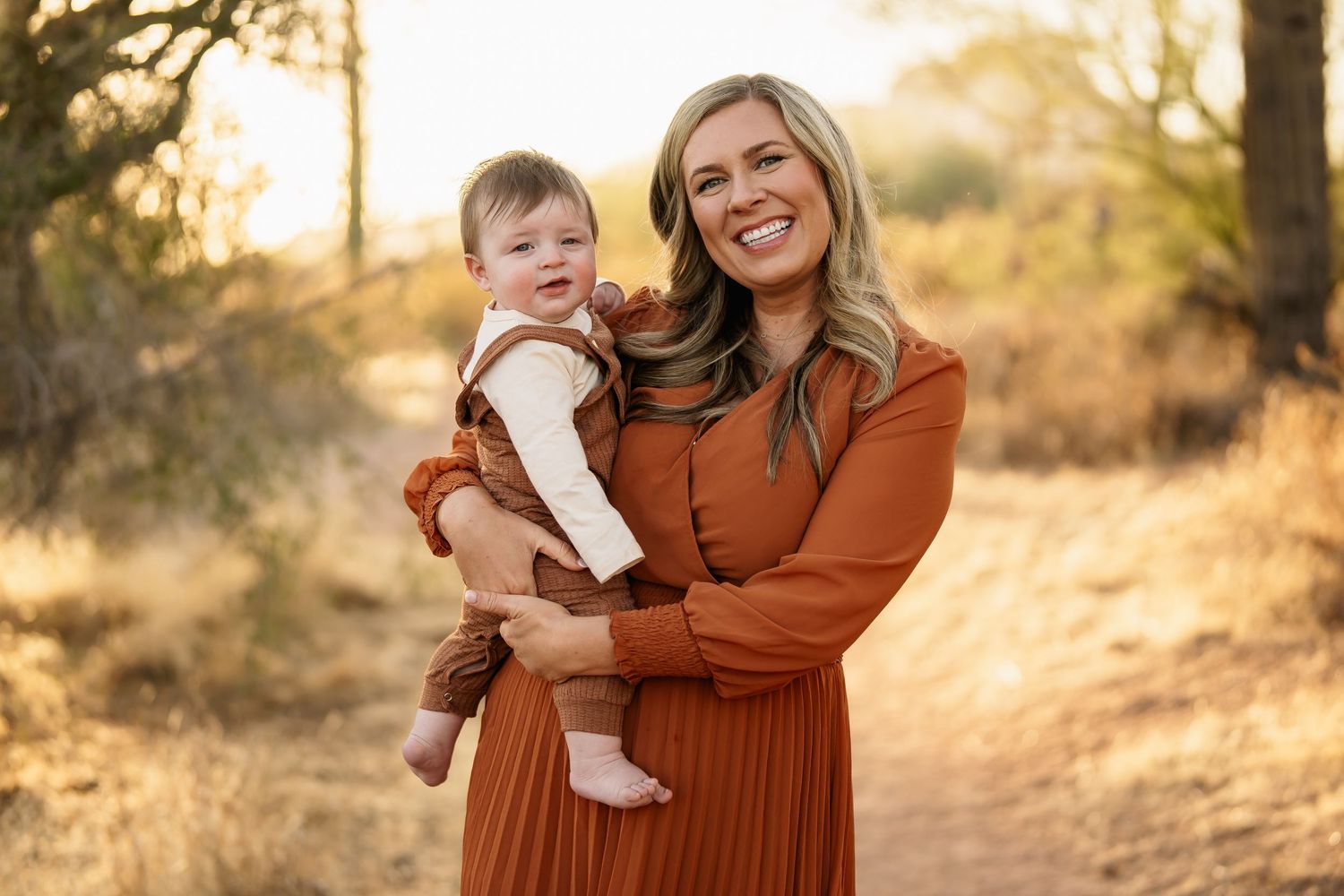 Joyful family embraces while standing in desert landscape during golden hour.