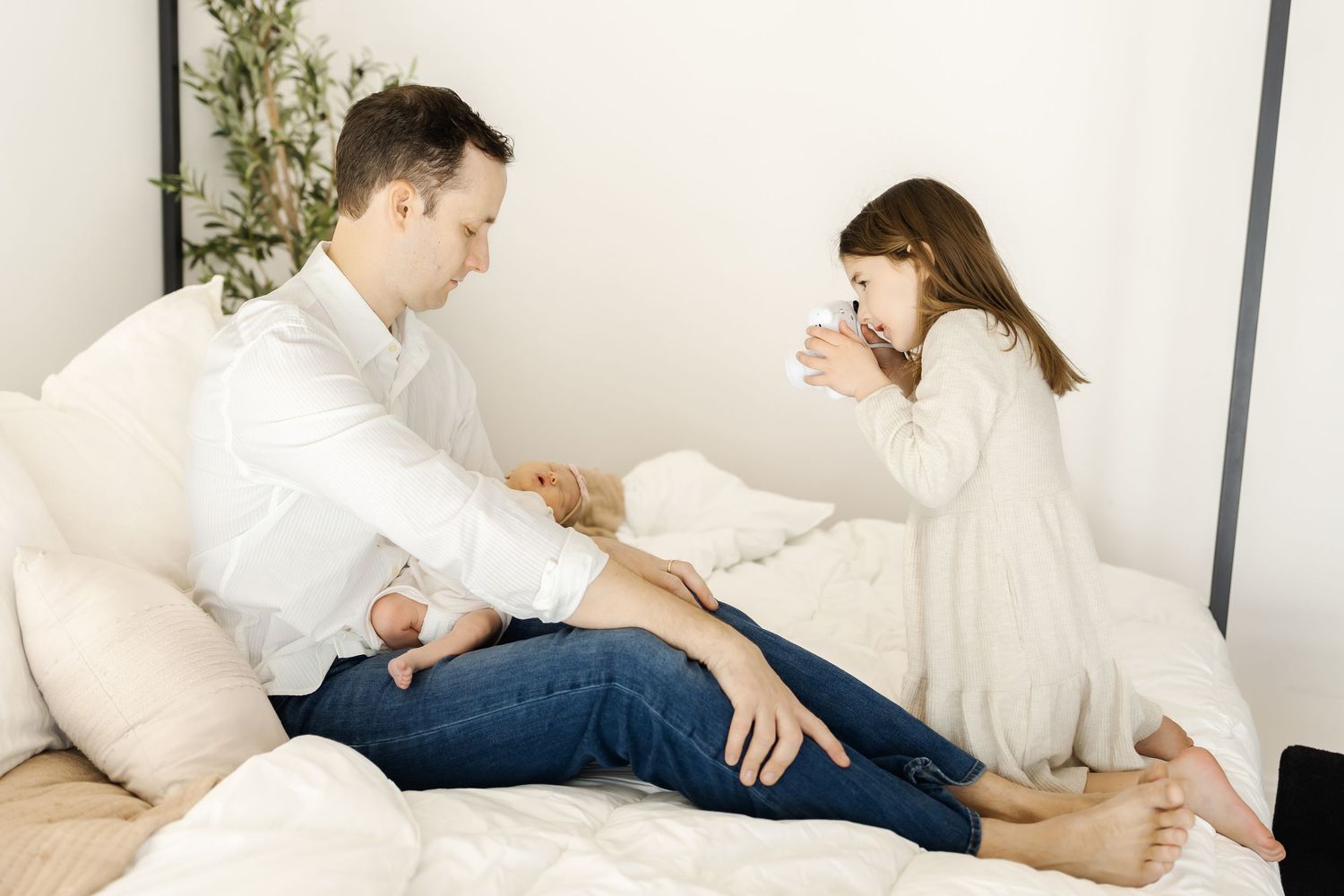 Family relaxing on a white couch in casual attire against a bright background.