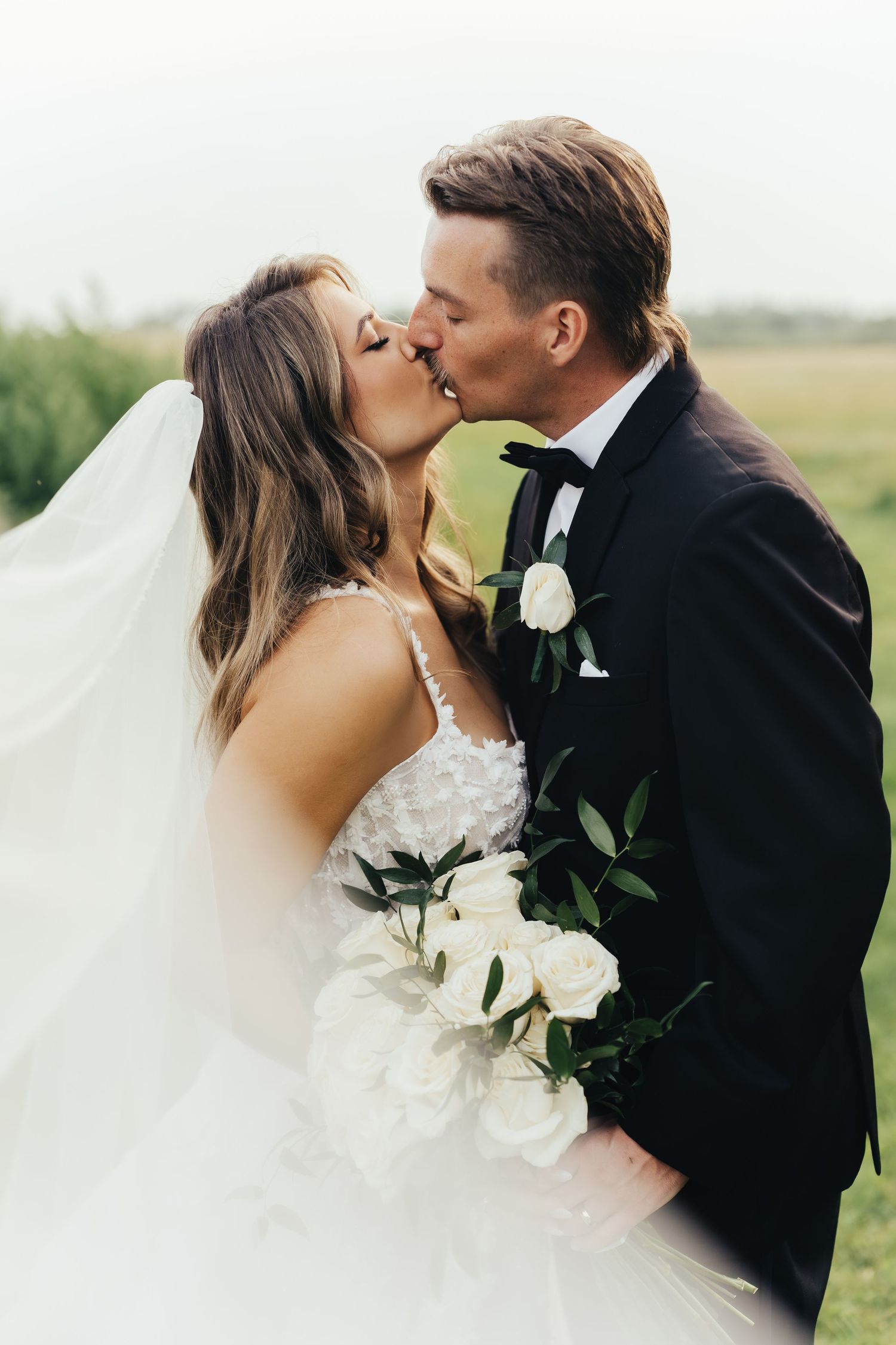 Romantic wedding couple sharing intimate moment against soft white background.