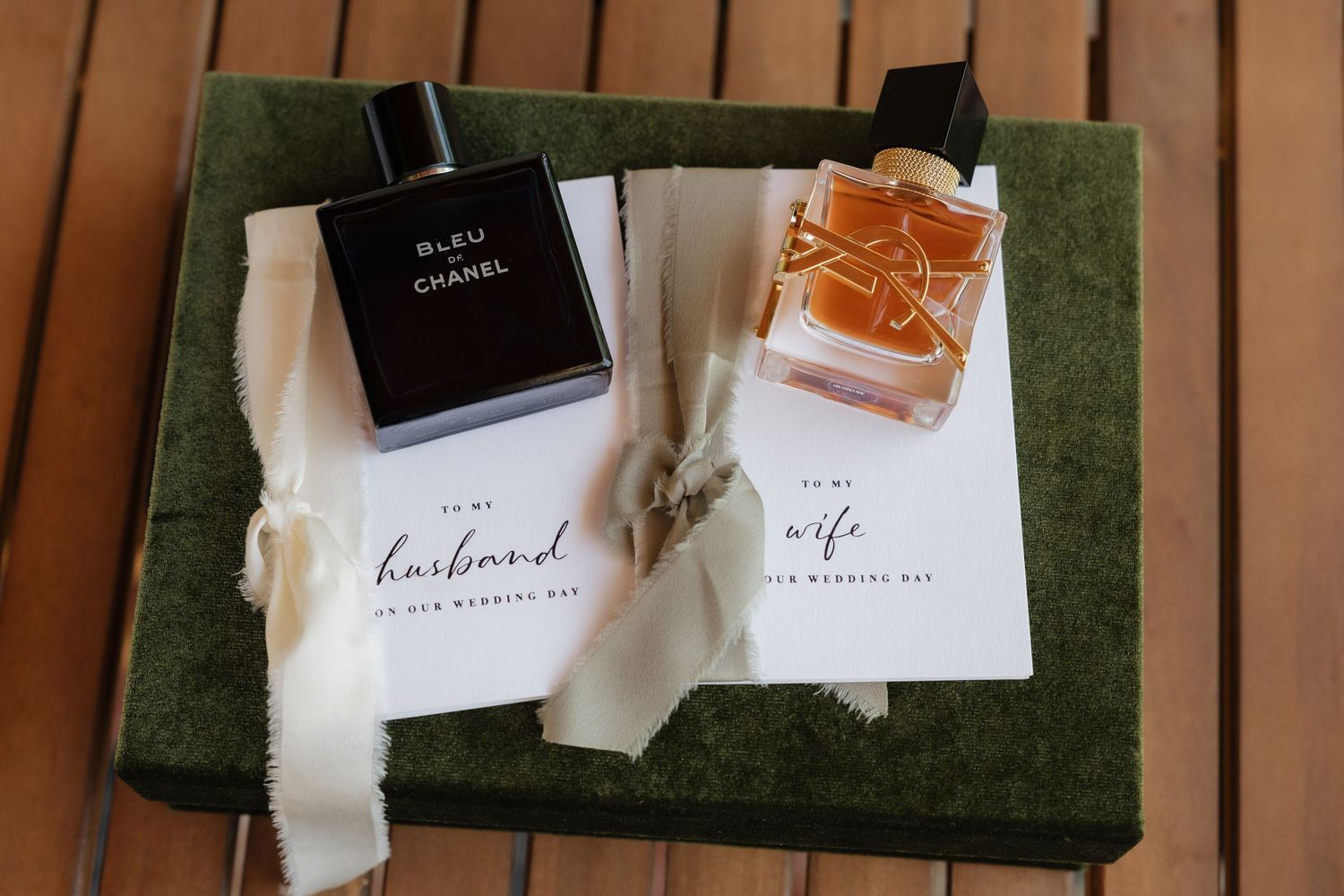 Bleu de Chanel cologne and amber perfume on green velvet box with husband and wife wedding day cards.
