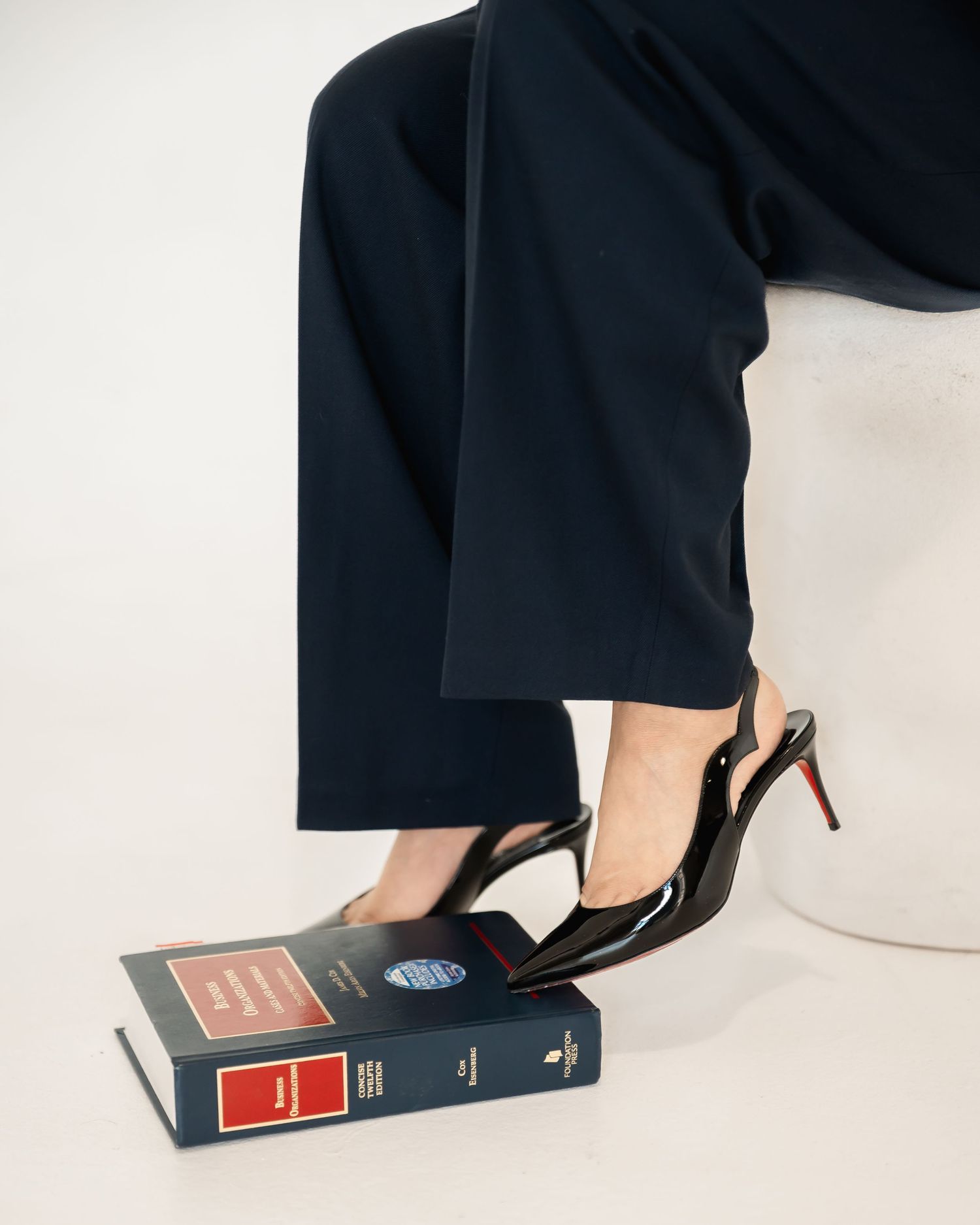 Styled product photo of black heels resting on stacked vintage books.