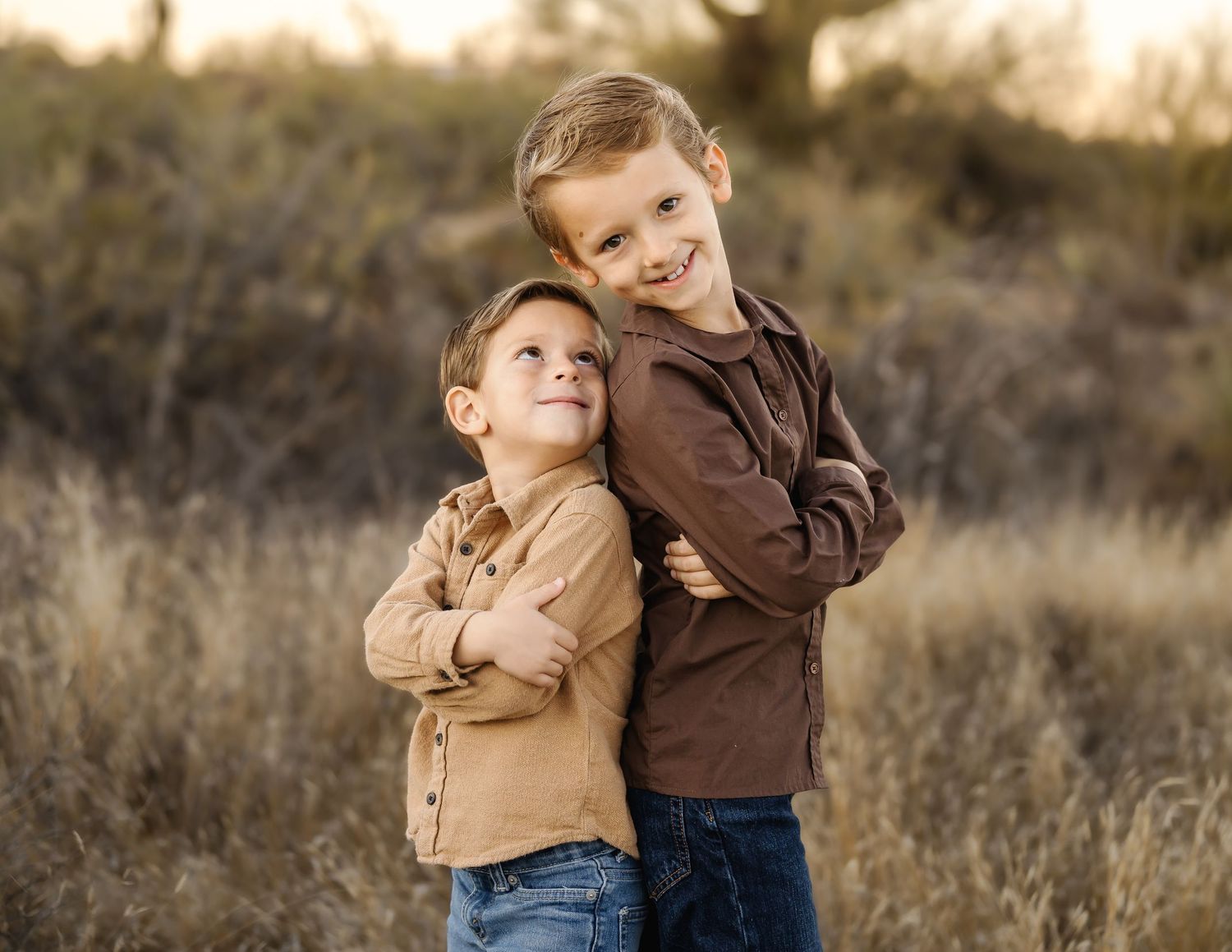 Children play and embrace in desert setting during golden hour.