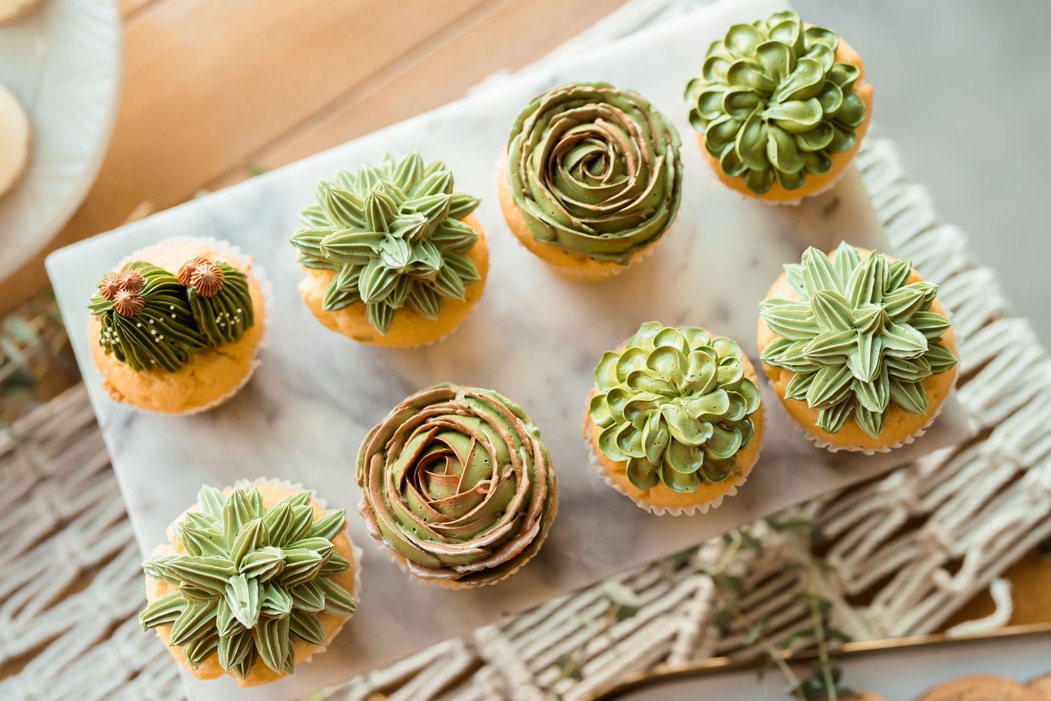 Elegant succulent-topped mini desserts arranged on rustic wooden surface.
