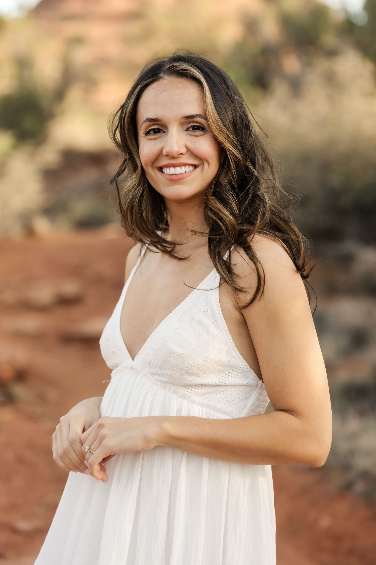 A white sundress flows in the desert breeze during a photoshoot at sunset.
