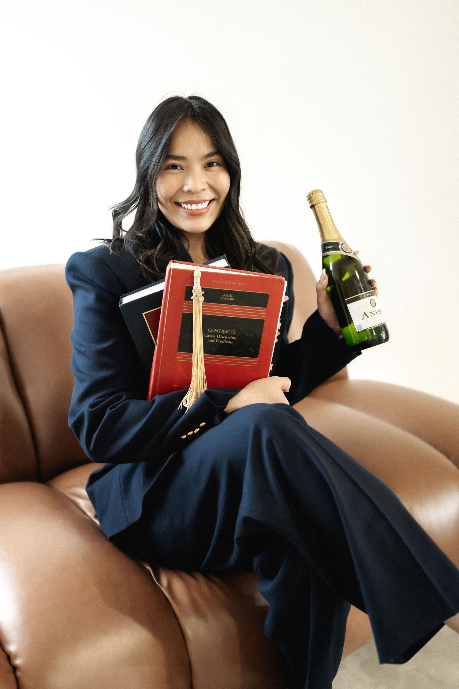 Someone relaxing on brown leather couch with books and champagne.