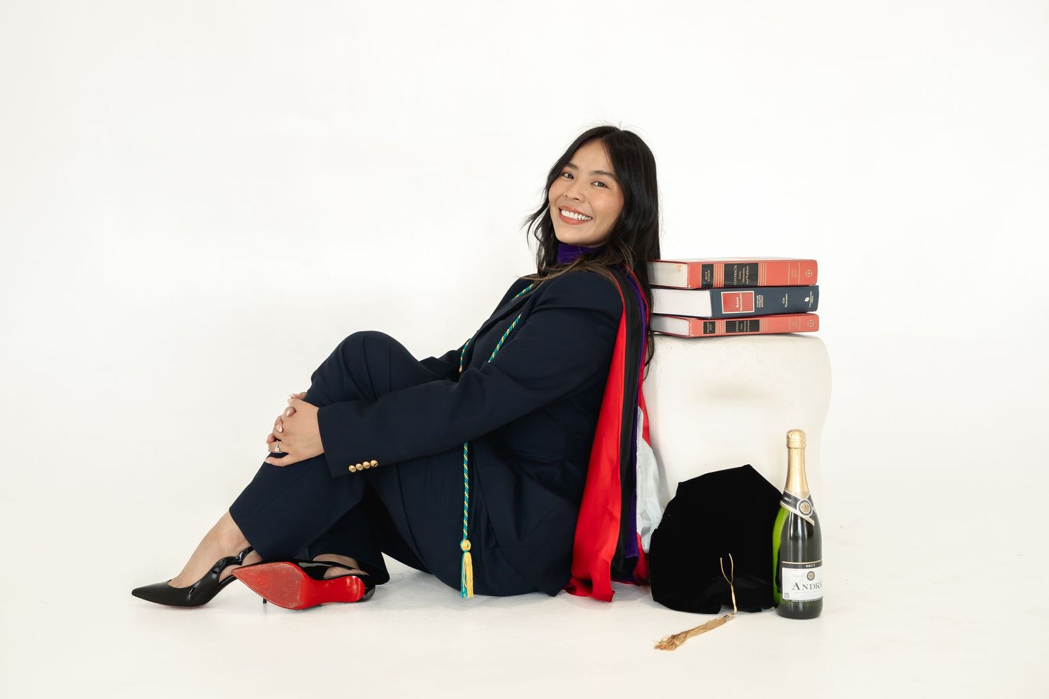 Creative graduation photo shoot with books and casual poses on white background.