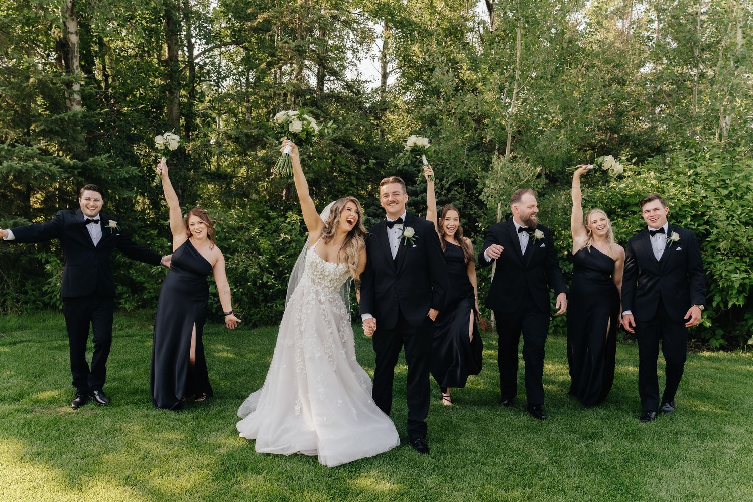 Wedding party poses on lush green lawn for formal group photos.