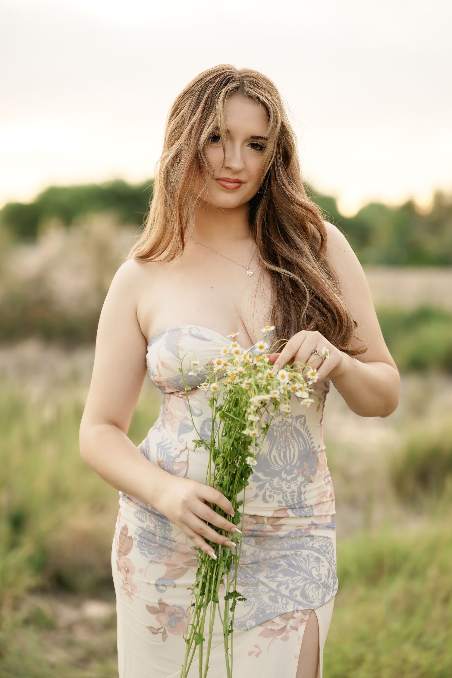 Delicate white wildflowers held against a floral patterned dress in a natural outdoor setting.