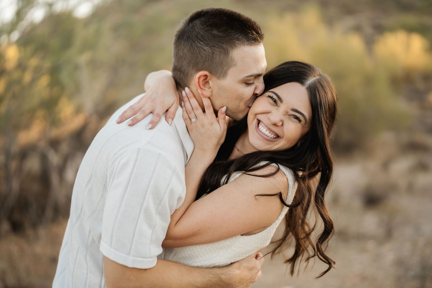 Couple sharing tender moments during desert engagement photoshoot.