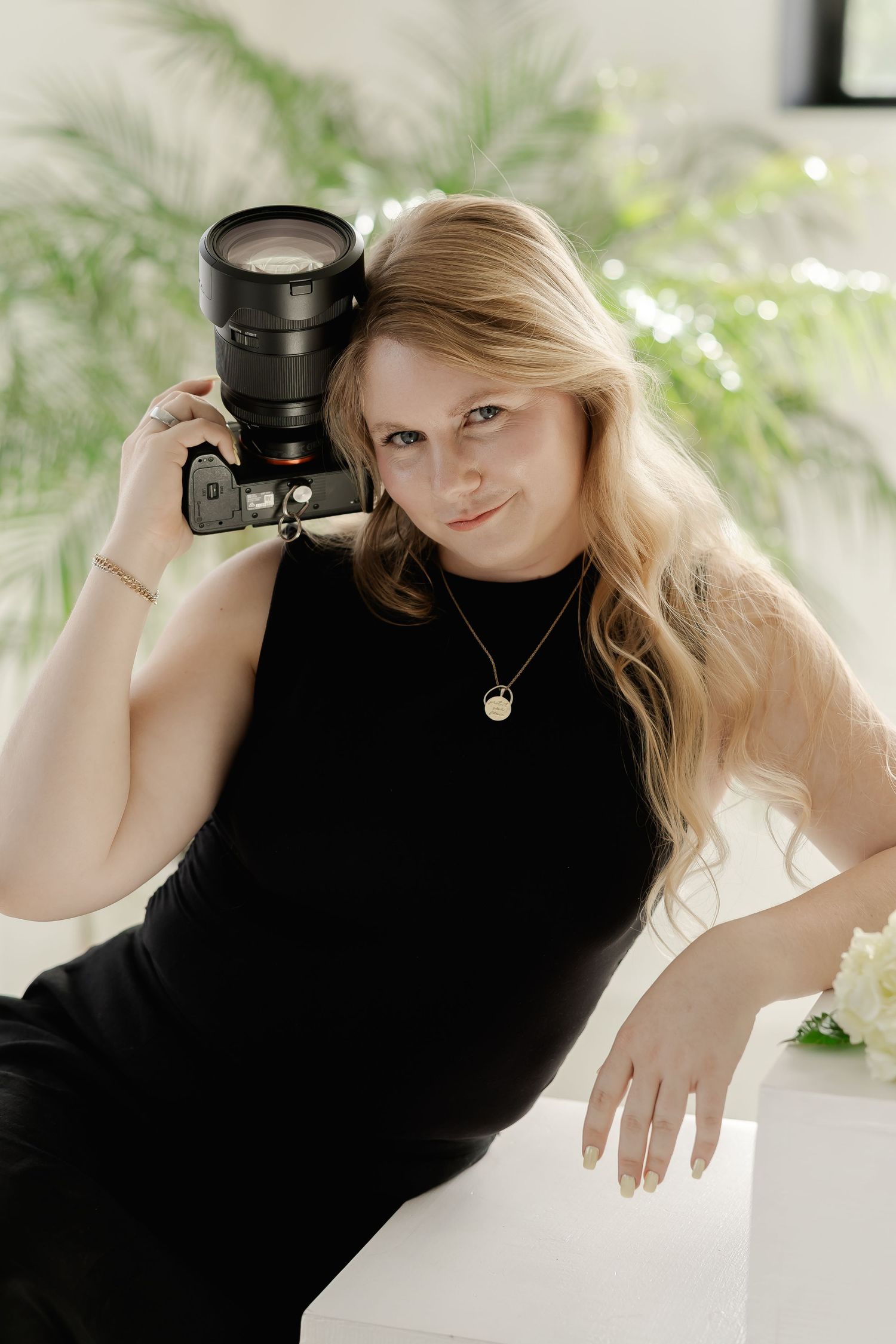 A series of artistic black and white photos showing a photographer holding a camera against a light background.