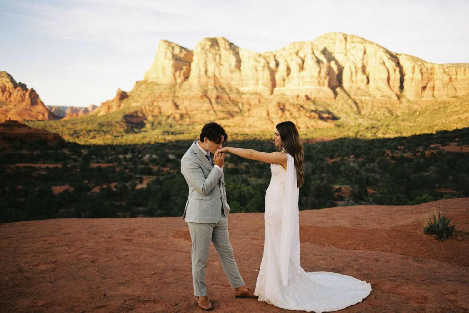 Couple shares a romantic first look moment during a desert elopement in Sedona, Arizona, with red rock formations.