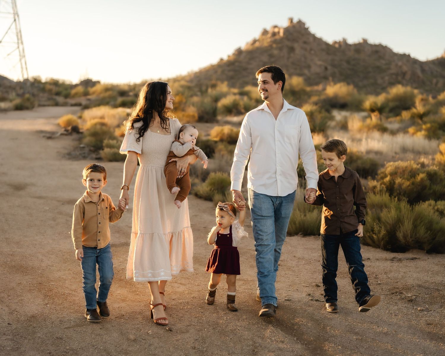Family walking together through desert brush at sunset.