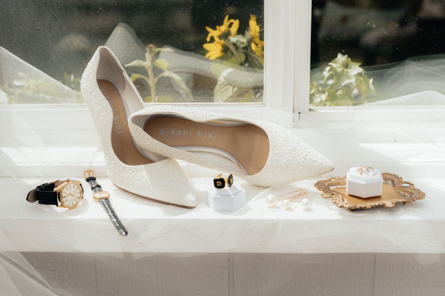 Elegant bridal shoes and accessories arranged on white surface with soft lighting.