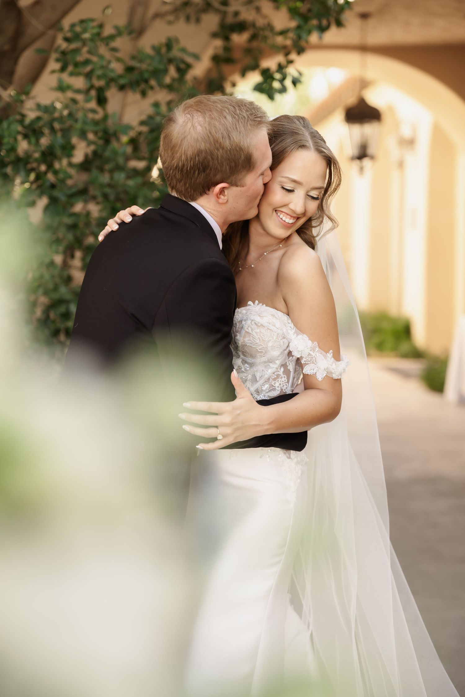 A romantic wedding moment captured under an outdoor colonnade.