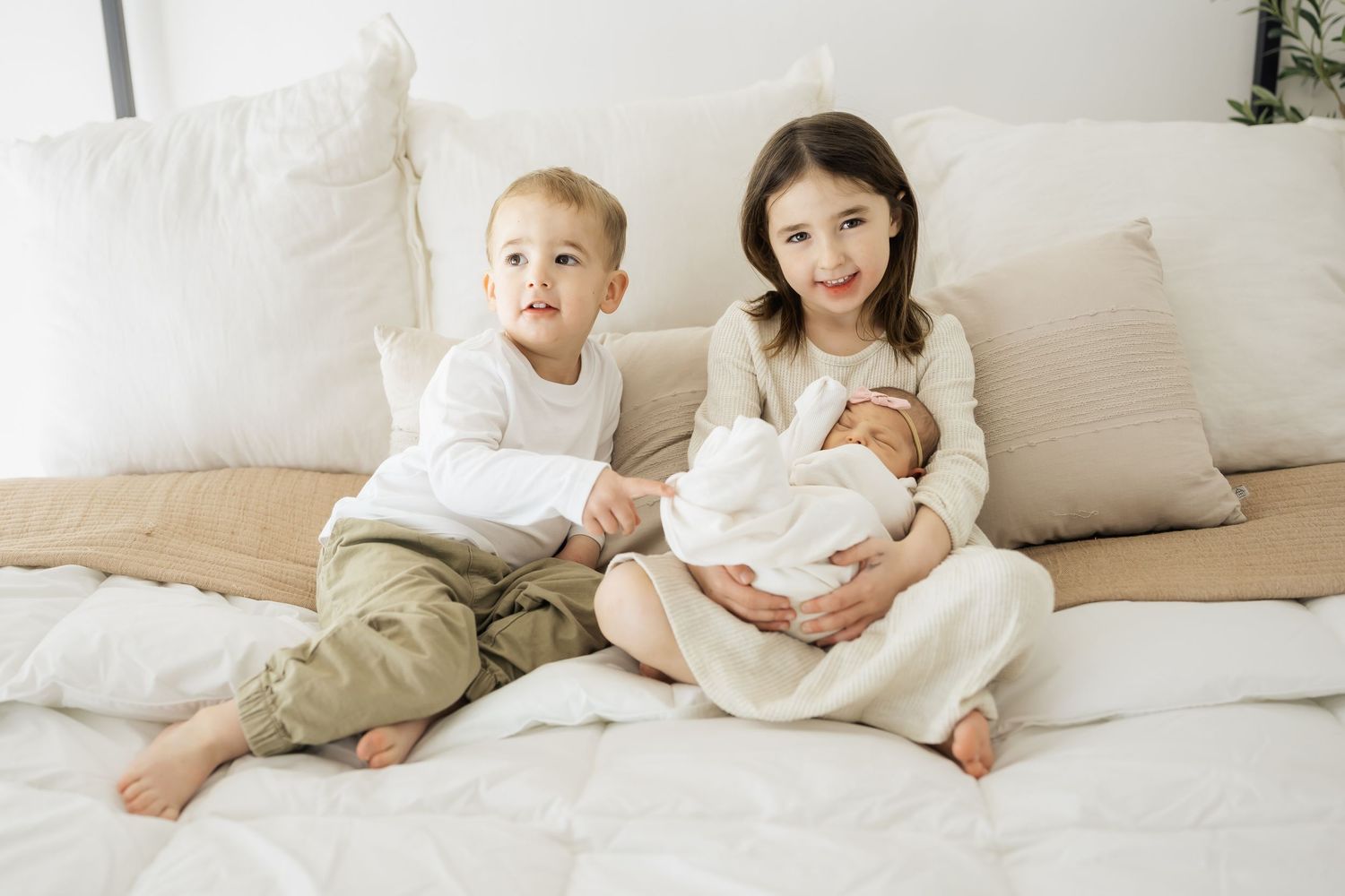 Family members relaxing together on white bedding in casual clothing.