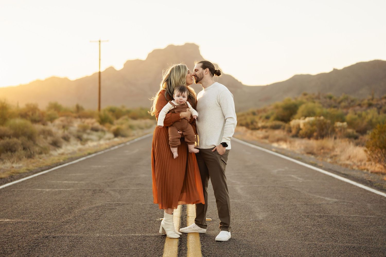Family walking together on desert road during sunset photoshoot.