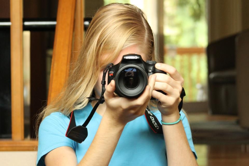 Photographer in blue shirt taking photos with professional camera equipment.