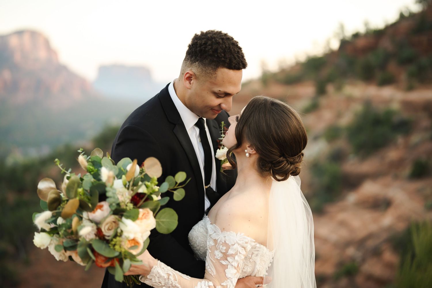 Romantic bride and groom share intimate moments in a beautiful desert landscape at sunset.