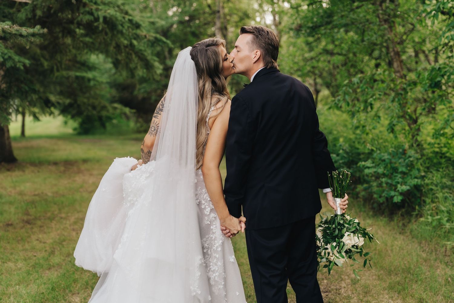 Romantic wedding couple embracing outdoors in formal attire.