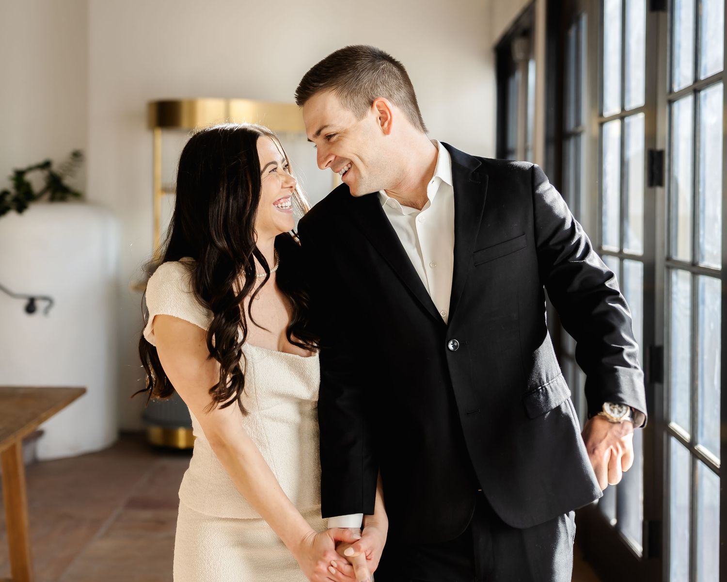 Romantic couple laughing together in a sunlit indoor setting with modern decor.