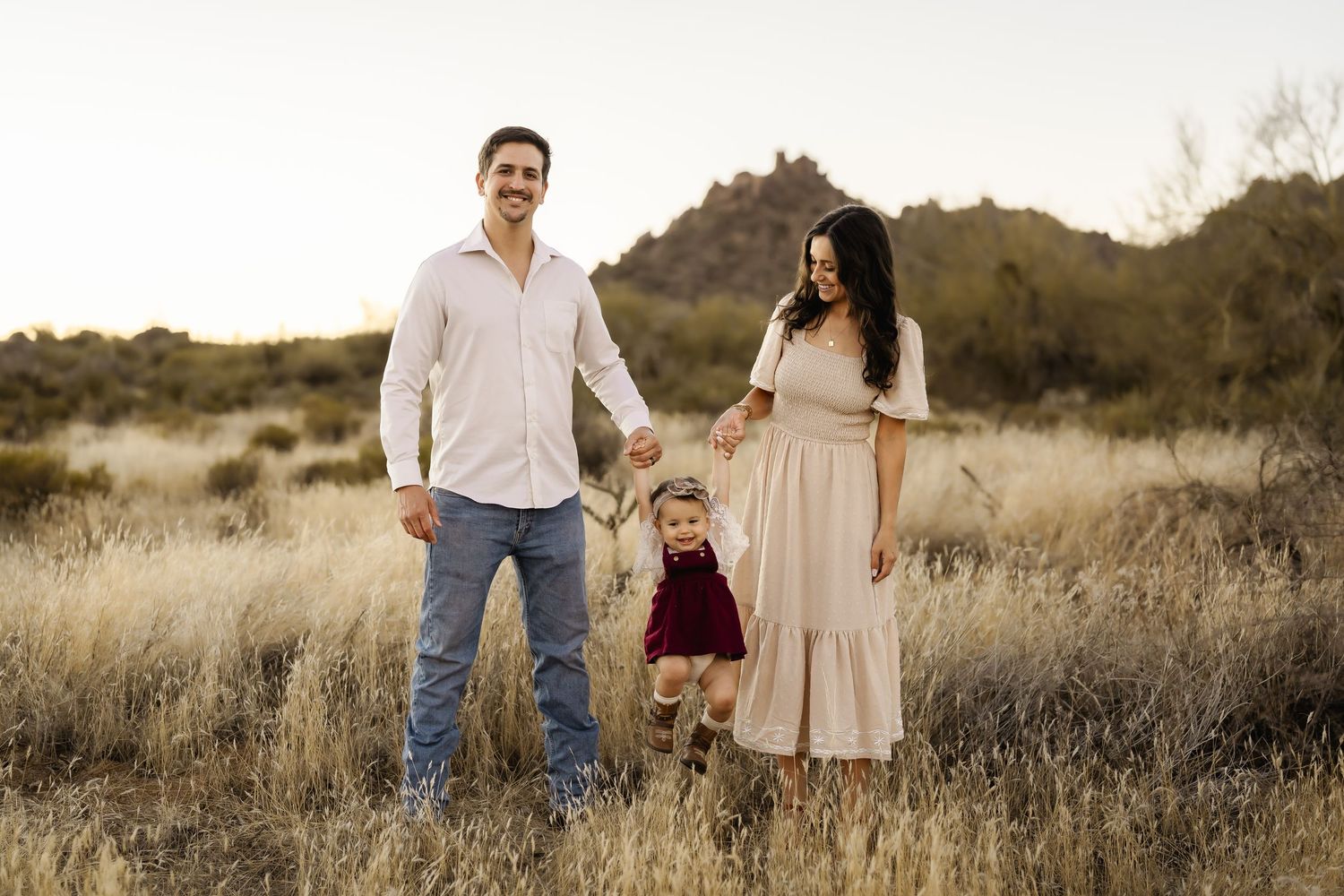 Family members walking hand in hand through desert landscape at dusk.